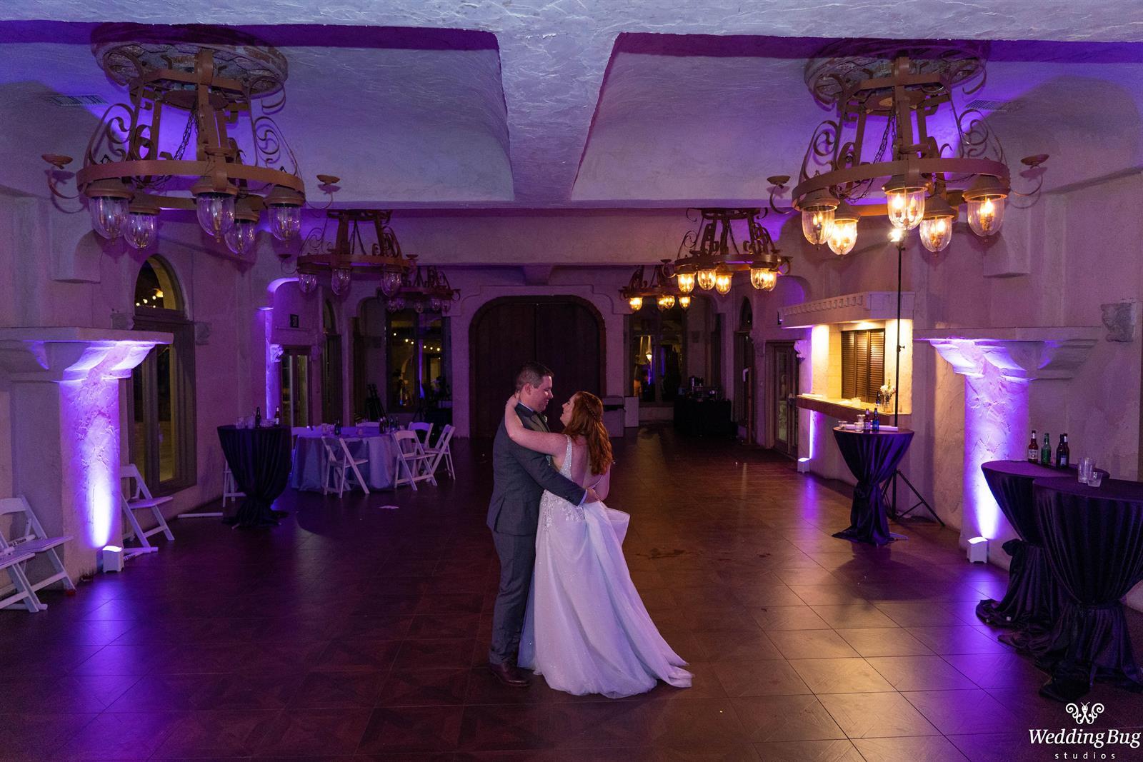 Bride and Groom dance alone, Purple Uplights in background Bride and Groom dance alone, Purple Uplights in background